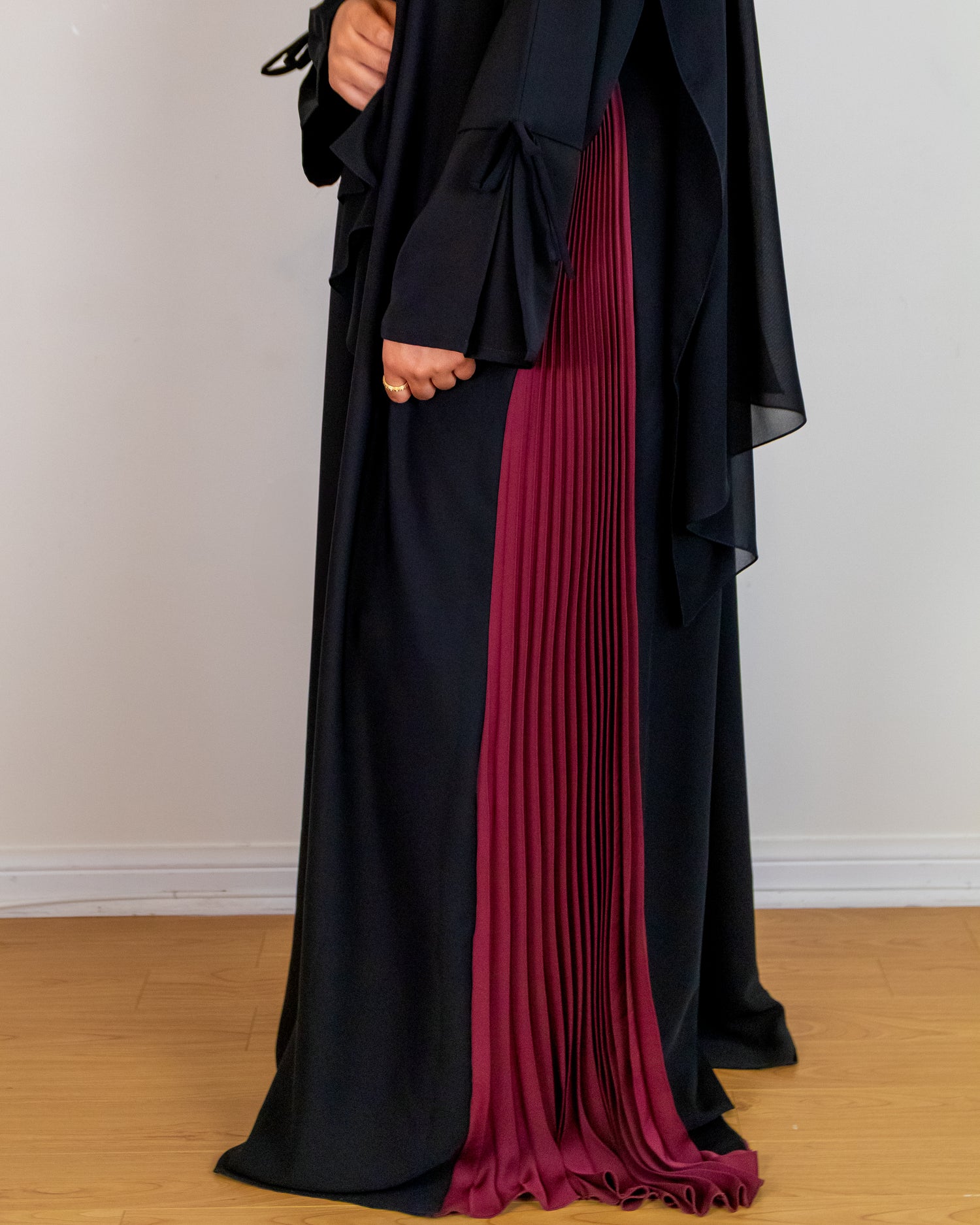Black and red abaya on a wooden floor with a white wall background